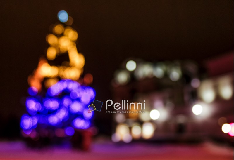 Abstract Christmas lights background at night. Christmas tree on the city square blurred with bokeh effect 