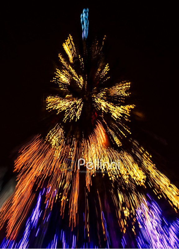 Abstract Christmas lights background at night. Christmas tree blurred with zoom effect 