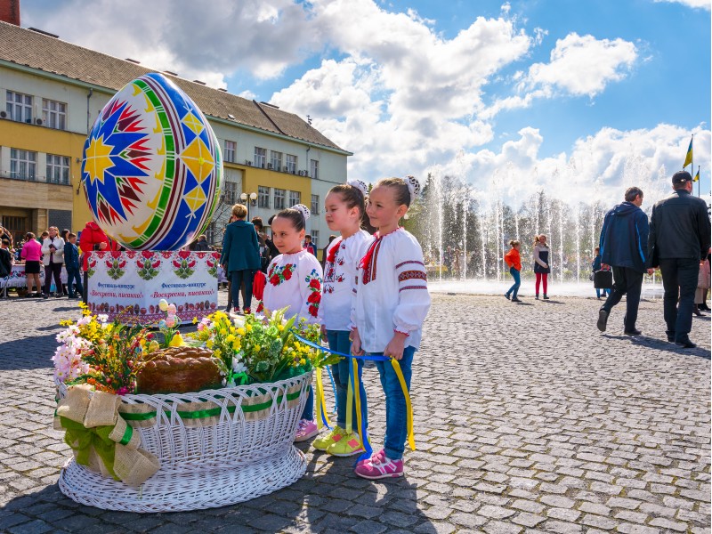 Uzhgorod, Ukraine - April 07, 2017: Celebrating Orthodox Easter in Uzhgorod on the Narodna square. Huge egg near the fountain on a warm springtime day. kids near the big basket with flowers