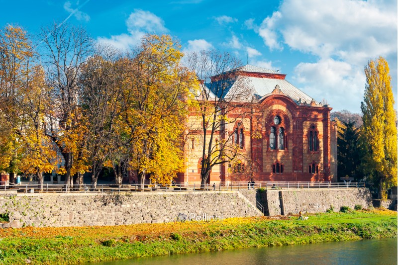 Uzhgorod, Ukraine - NOV 10, 2012: Philharmonic Orchestra Concert Hall on the bank of the river Uzh in autumn. former building of synagogue is a popular tourist attraction. beautiful sunny weather with yellow foliage