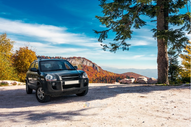 SUV on the parking lot in mountains. beautiful mountainous scenery with huge rocky formation in the distance. wonderful deep autumn landscape. travel europe by car concept