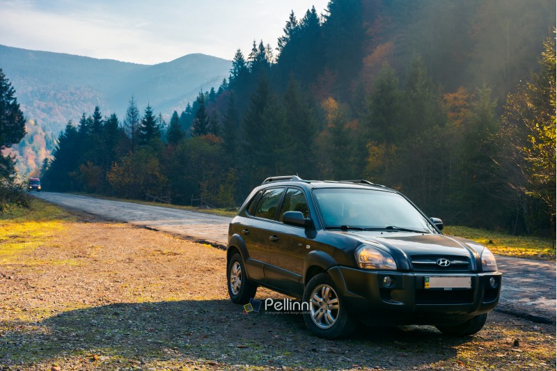 SUV on the road side in forested mountain. lovely transportation scenery on foggy autumn sunrise. travel by car concept