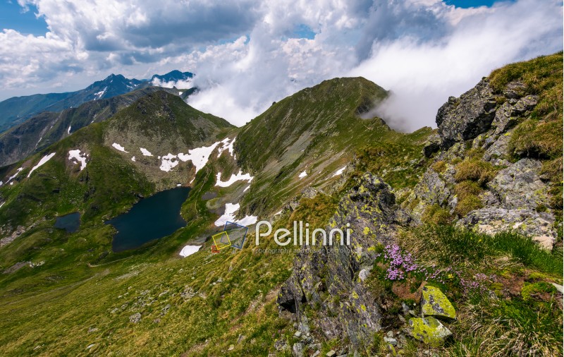 edge of steep slope on rocky hillside in cloudy weather. dramatic scenery with snow near glacier in Fagaras mountains