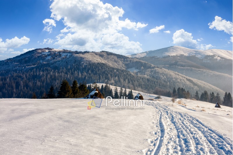haystack near the path through agricultural field on snowy hillside at foggy morning in winter mountains