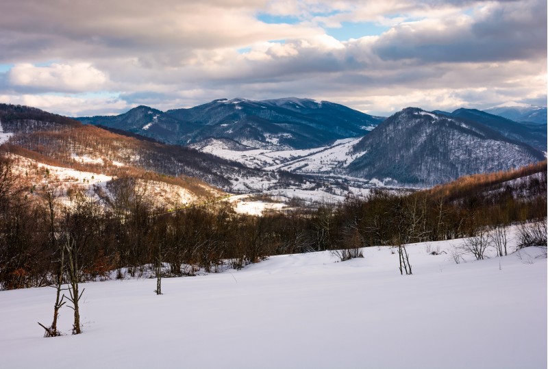 beautiful mountainous countryside in afternoon. gorgeous winter landscape with cloudy sky and snowy slopes