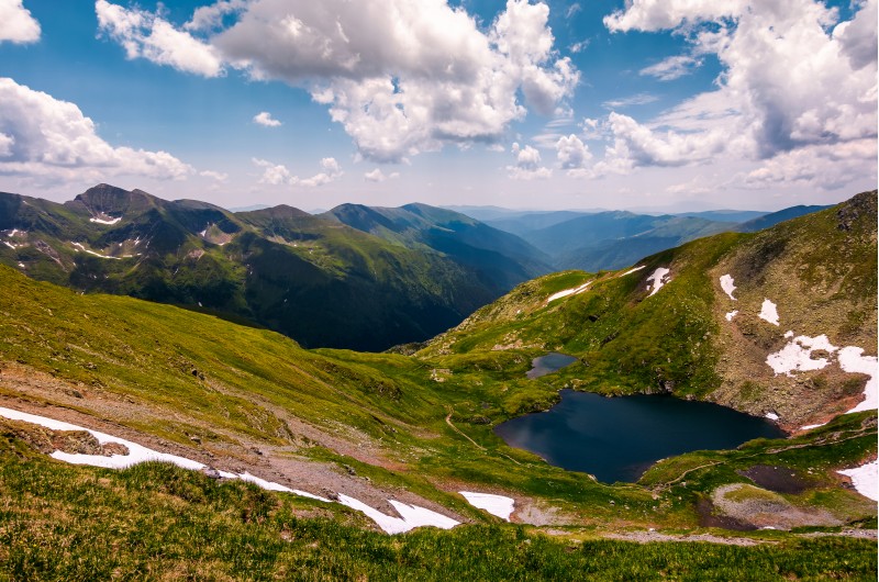 beautiful summer landscape of Fagaras mountains. stunning view from the top of a hill under the sky with clouds. lovely glacier on grassy slope over the deep long valley of Southern Carpathians