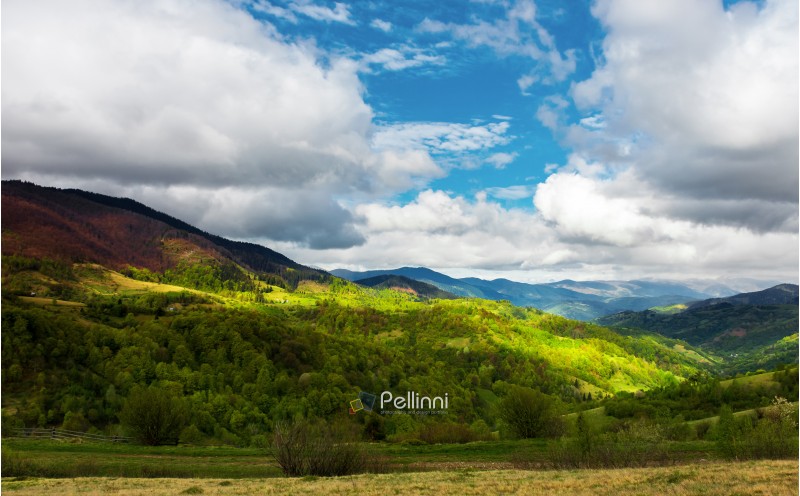beautiful sunny morning in mountains. carpathian countryside in spring. village in the distant valley at the bottom of the ridge. cloudy sky