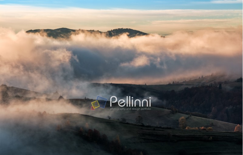 clouds and fog rising over countryside. rural fields on hills in gorgeous autumn sunrise