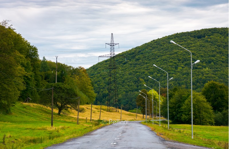 country road in mountains. lights and power line tower along the road