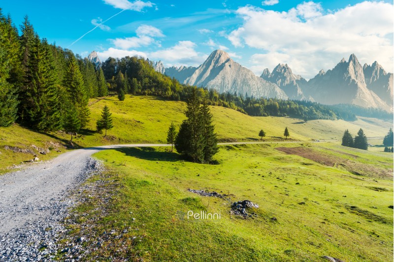 country road winds through the valley. mountains with high rocky peaks in the distance. composite image of a beautiful landscape at hazy sunrise