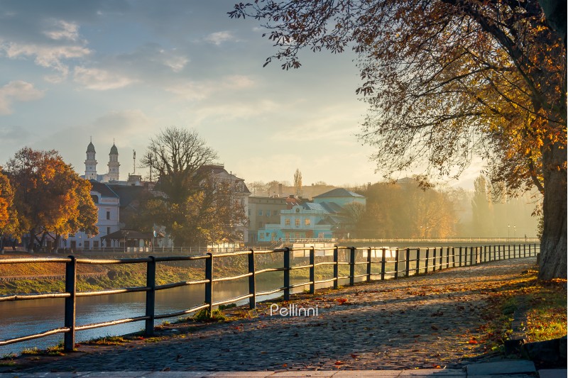 embankment of the river Uzh. beautiful urban scenery with colorful foliage on trees in morning haze. bridge, theater, cathedral towers and other landmarks of Uzhgorod in the distance. Nov 10, 2012