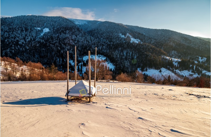 empty haystack shed on snowy hillside. beautiful winter morning in mountainous rural area of TransCarpathia