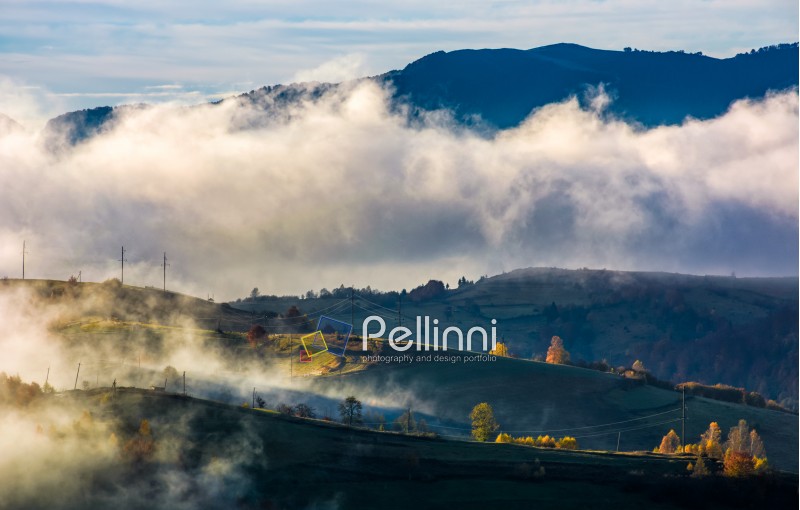fog rising over the rural hills in morning light. dramatic Carpathian countryside autumnal scenery