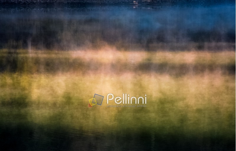 closeup of foggy forest lake surface at sunrise. beautiful nature background of colorful smoke rising over the water