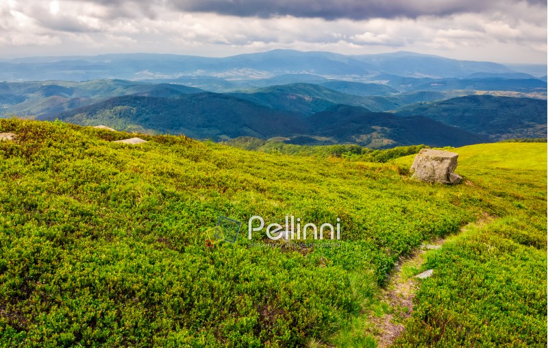 summer mountain landscape. footpath down the hill through mountain ridge to valley. huge boulders on grassy slope. beautiful Carpathian nature scene