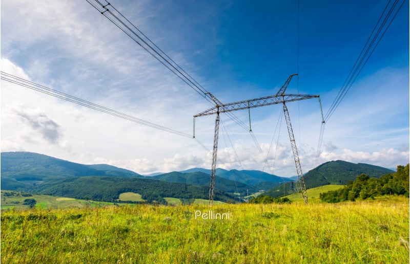 high voltage power lines tower in Carpathian mountains. lovely green energy industry concept. beautiful landscape in autumn with blue sky and some clouds