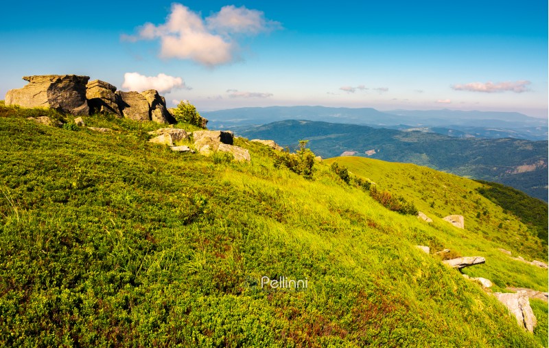 mountainous landscape in summer. lovely scenery with rocky formation on the grassy hill under the blue sky with some clouds.
