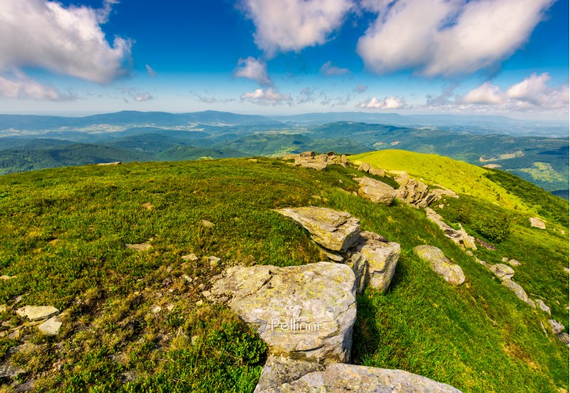 mountainous landscape in summer. lovely scenery with rocky formation on the grassy hill under the blue sky with some clouds.