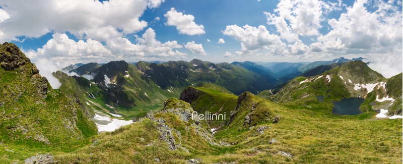 panorama of Fagaras mountain ridge in summer. beautiful view in to the valley of beautiful landscape with gorgeous cloudscape. rocky cliffs above the grassy slopes with some snow. 