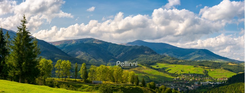 panorama of mountainous urban area. lovely countryside landscape in early autumn. trees along the road down the hill. village down in the valley and clouds on a blue sky over the distant ridge