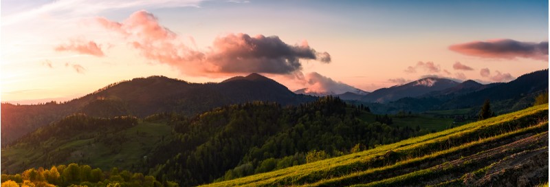 panorama of mountains at sunset. beautiful landscape with purple clouds and green hills in springtime