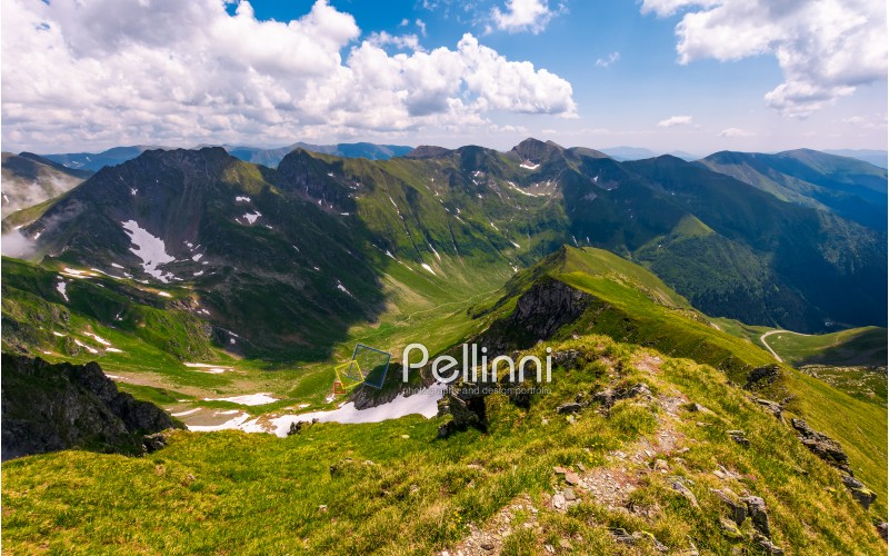 path along the mountain ridge with snow on hills. Gorgeous summer scenery in Fagaras mountains of Romania