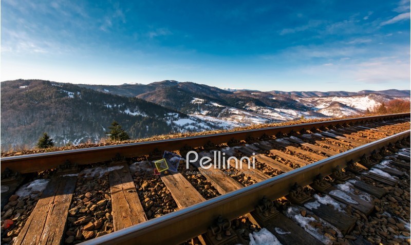 railroad in mountains with snowy slopes. lovely transportation scenery on winter sunny day