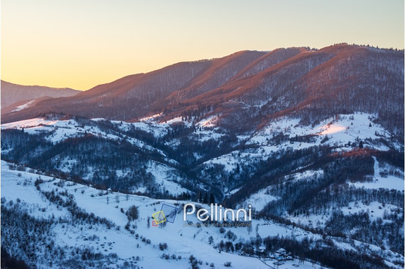 village in mountains covered with snow under a red winter sunrise