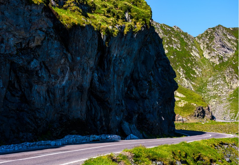 road under the cliff in high mountains. transportation background with dangerous aspect