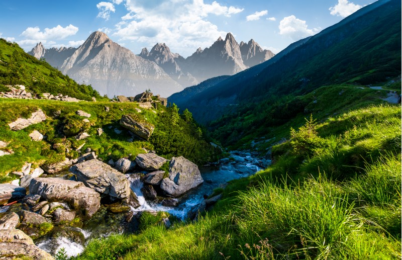 stream among the rocks in grassy valley. gorgeous summertime composite landscape with High Tatra mountain ridge in a distance