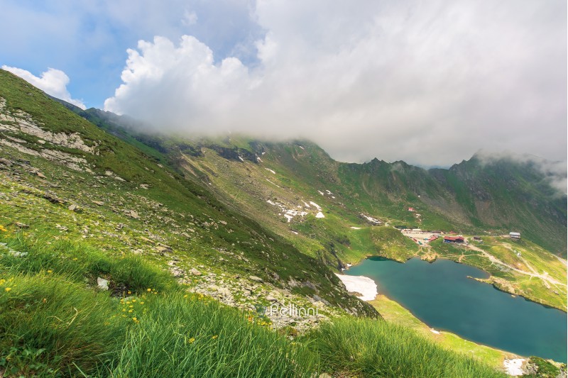 summer time in romanian carpathians. beautiful landscape of fagaras mountains. lake balea down in the valley. cloud approaching the ridge. view from the slope of Șaua Caprei