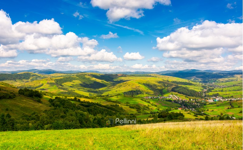 village in the valley of Carpathian mountains. lovely countryside scenery in early autumn with clouds on a blue sky over the distant ridge