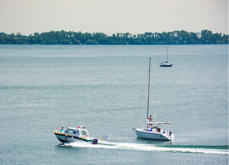 water police patrols Zemplinska Sirava lake, Slovakia. two sailboats stand still, safe vacation in summer