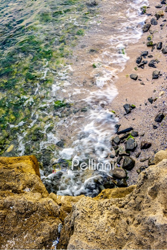 wave rolls onto the rocks on the sandy sea coast