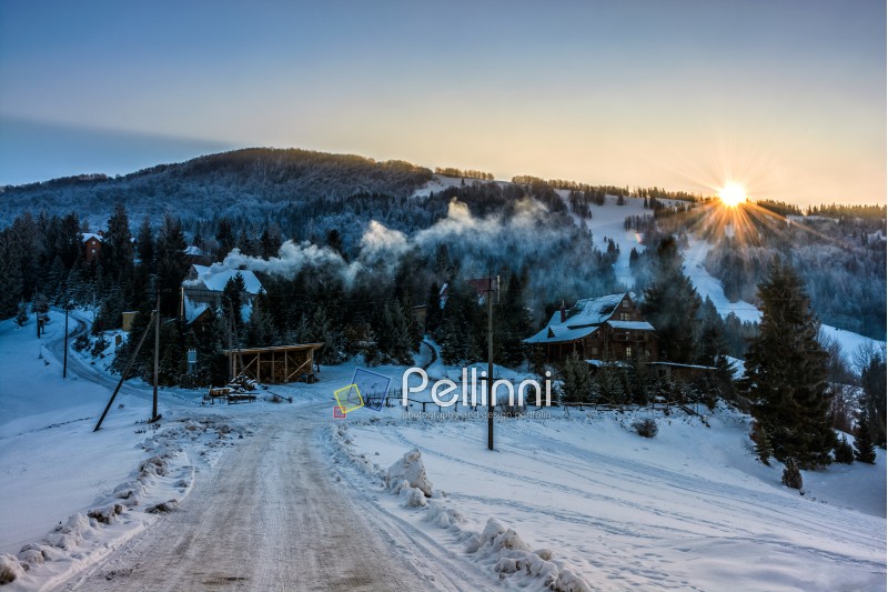 village near the forest in mountainous area in winter carpathian landscape in evening light