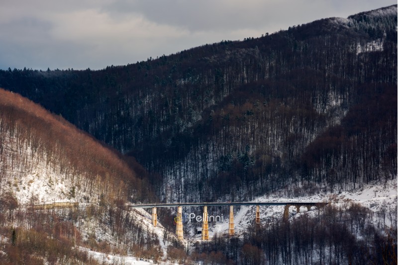 winter rail road transportation in mountains. old viaduct between the hills