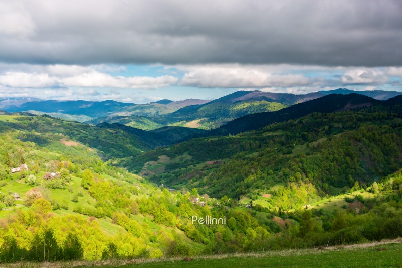 wonderful afternoon of mountainous countryside. small village in the valley, some houses on the hill. cloudy grey sky. beautiful springtime nature scenery.
