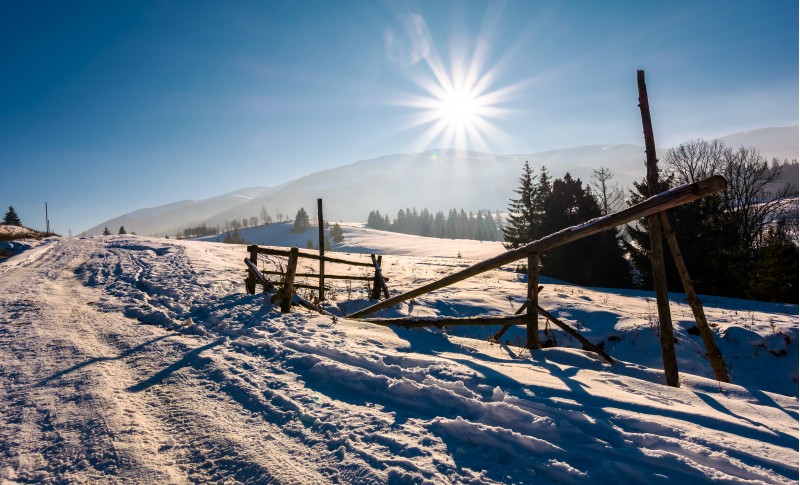 wooden fence on snowy meadow. lovely rural scenery on a bright sunny day. location Pylypets, Ukraine