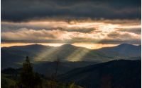 Carpathian valley lit by sunbeams. Spectacular mountain landscape at cloudy sunset