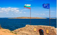 SOZOPOL, BULGARIA - SEPTEMBER 08, 2013: Northen tower with entrance to the fortress of sozopol. European and Bulgarian flag wave abow the Black Sea shore. st Ivanand and st Peter islands are seen in the distance