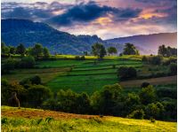agricultural fields with haystacks on hills in mountainous rural area at sunrise. dramatic countryside landscape