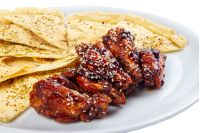 beer snack on the white plate. grilled chicken wings with italian pita bread chips