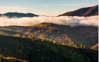 cloud rising above the rolling hills, gorgeous autumnal scenery in mountains at sunrise