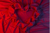 love card. heart made of a red fabric in blue light