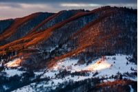 hillside in red light on winter sunrise. beautiful nature scenery in mountains