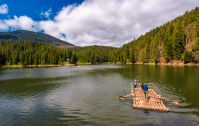 Synevyr, Ukraine - May 09, 2017: wooden raft with tourists on Synevyr lake. Beautiful springtime nature scenery in the most visited location of Carpathian mountains