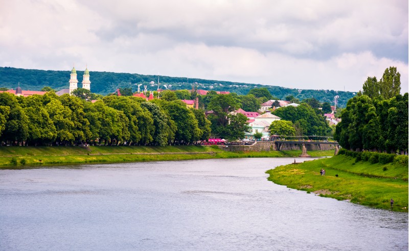Beautiful cityscape of Uzhgorod town in summer. Embankments with linden and chestnut alley lead to ancient part of a town. Puppet theater and domes of Greek Catholic Cathedral seen in the distance