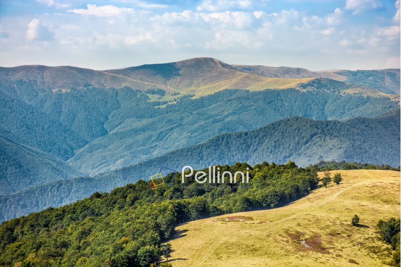 Polonyna Krasna Range of Carpathian Mountains with its peaks, hills, meadows and forests under the blue sky with clouds in late summer day