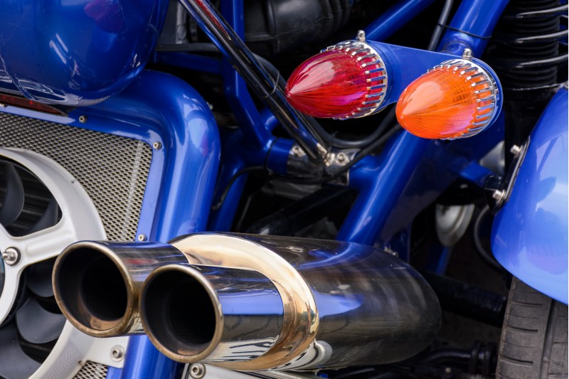back side of a blue motorcycle. lovely detail shot of lights and shiny exhaust pipes