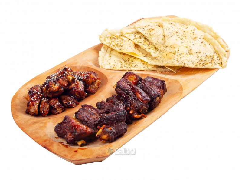beer snack on the wooden plate. grilled pork ribs and chicken wings with italian pita bread chips